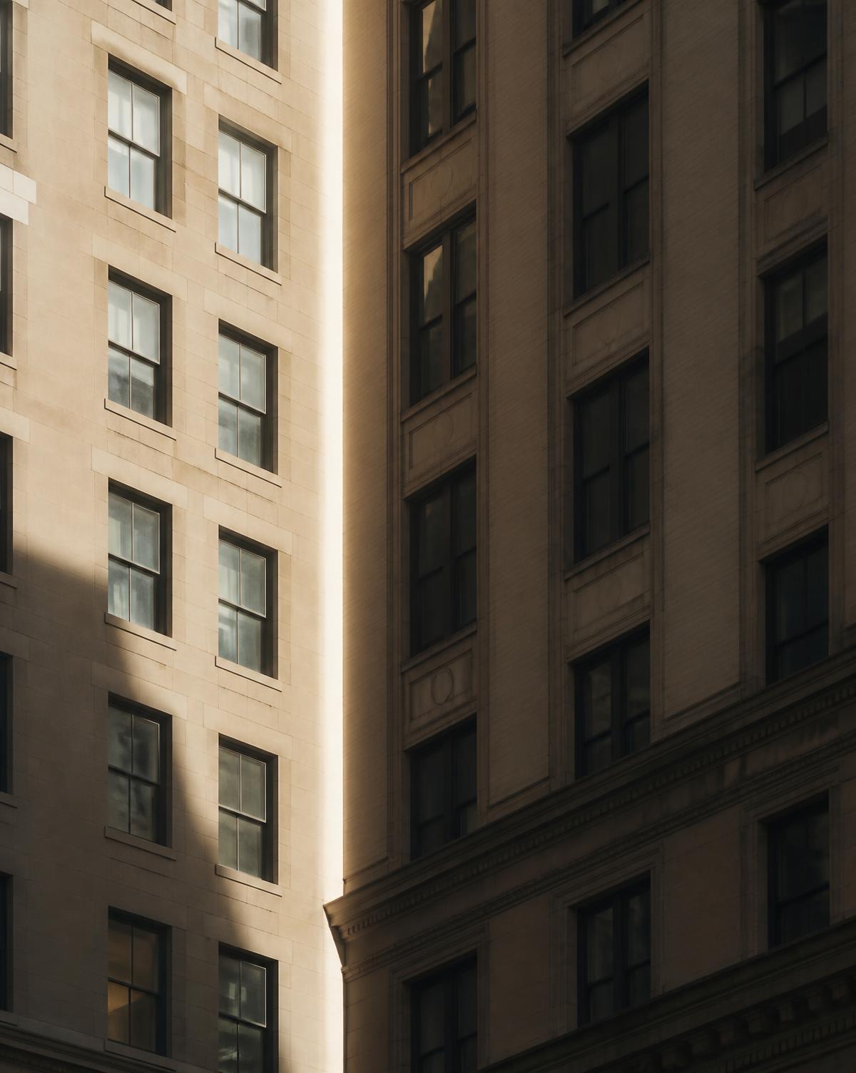 Two building facades meeting along a seam of light